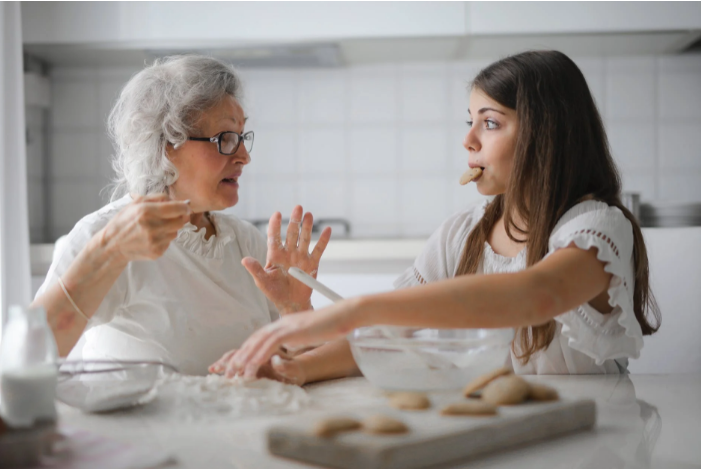Gray haired woman bakes cookies with teenage girl