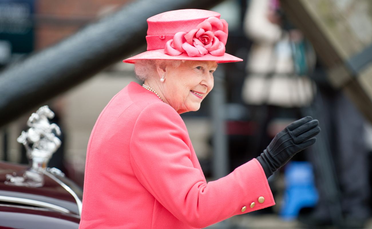 Queen Elizabeth II wearing full pink whilst smiling