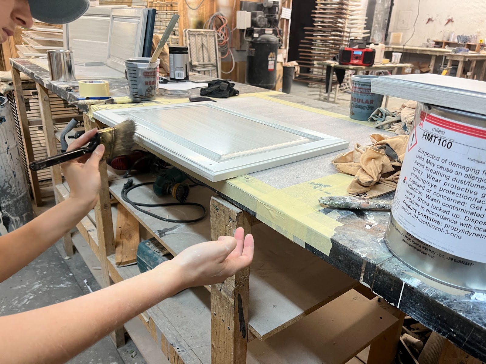 Brush & Roll Painting crew lead brushing grey glaze on the edge of a white cabinet door.