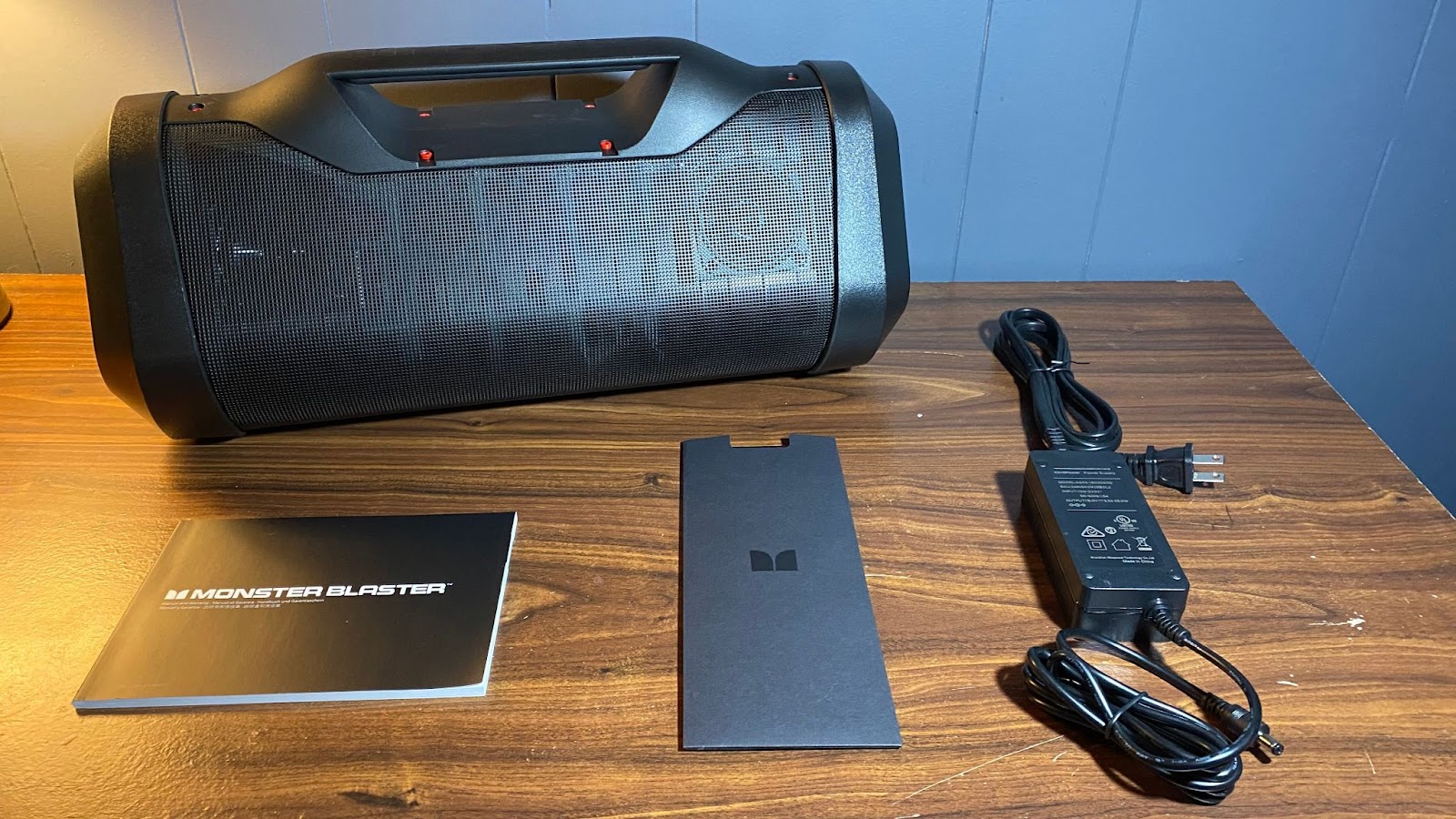 Monster Blaster 3.0 speaker on a table with the manual, sticker letter and power adapter displayed after unboxing.