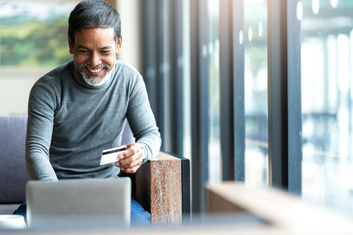 Man happily using his credit card and laptop