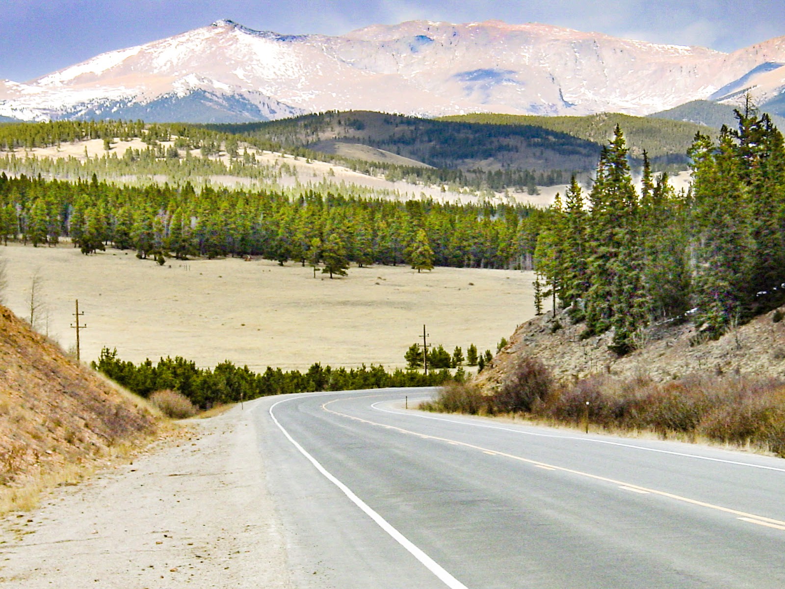 Road turns with snowy mountains in the distance. 