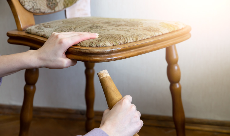 Someone putting a chair leg back on a chair