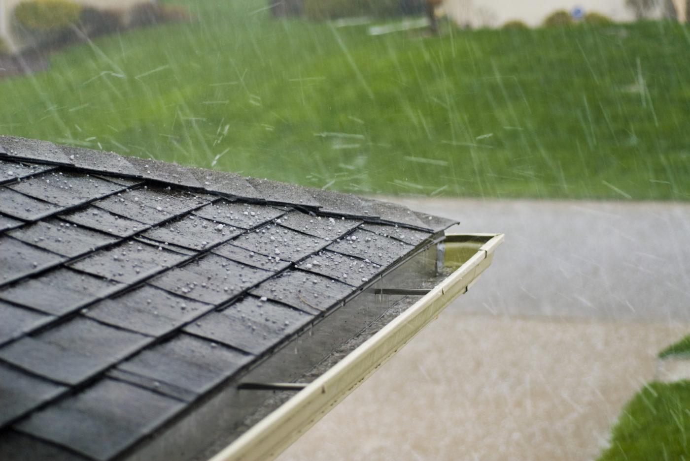 Weserve, gutter on top of a house with black roof with a cover on top of it with rain coming down