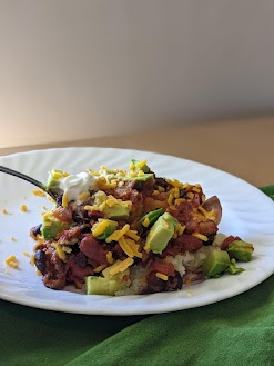 Cheese, avocado, and sour cream on top of chili with baked potato