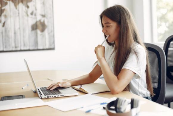 Young student sitting at the table and use the laptop Free Photo