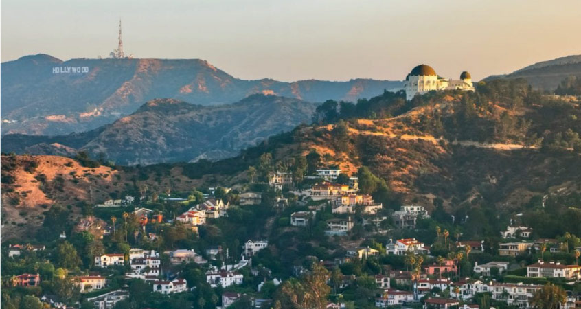 Aerial view of Los Feliz, Los Angeles. Homes are built into the hills and Griffith Park and the Hollywood sign can be seen in the distance. 