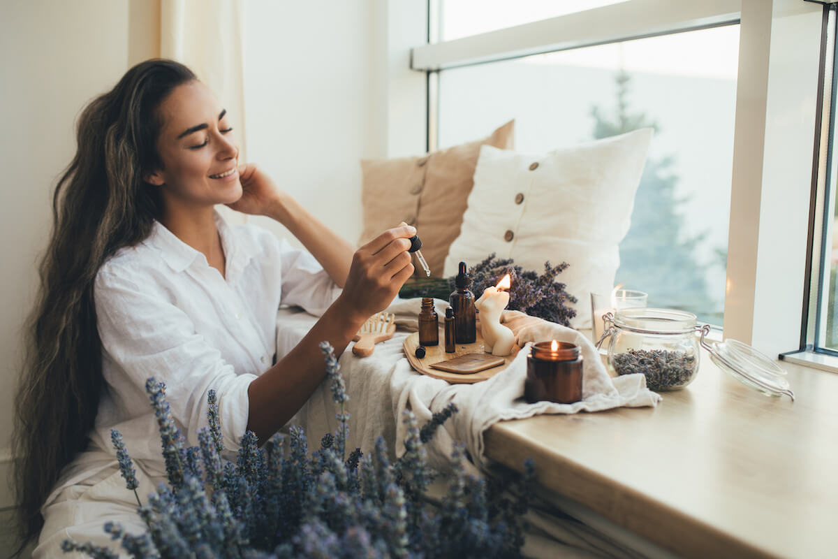 Woman using essential oil dropper in cozy bedroom