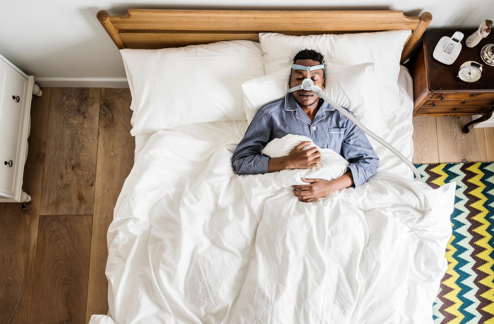 A man asleep in bed with a CPAP machine over his face to treat sleep apnea