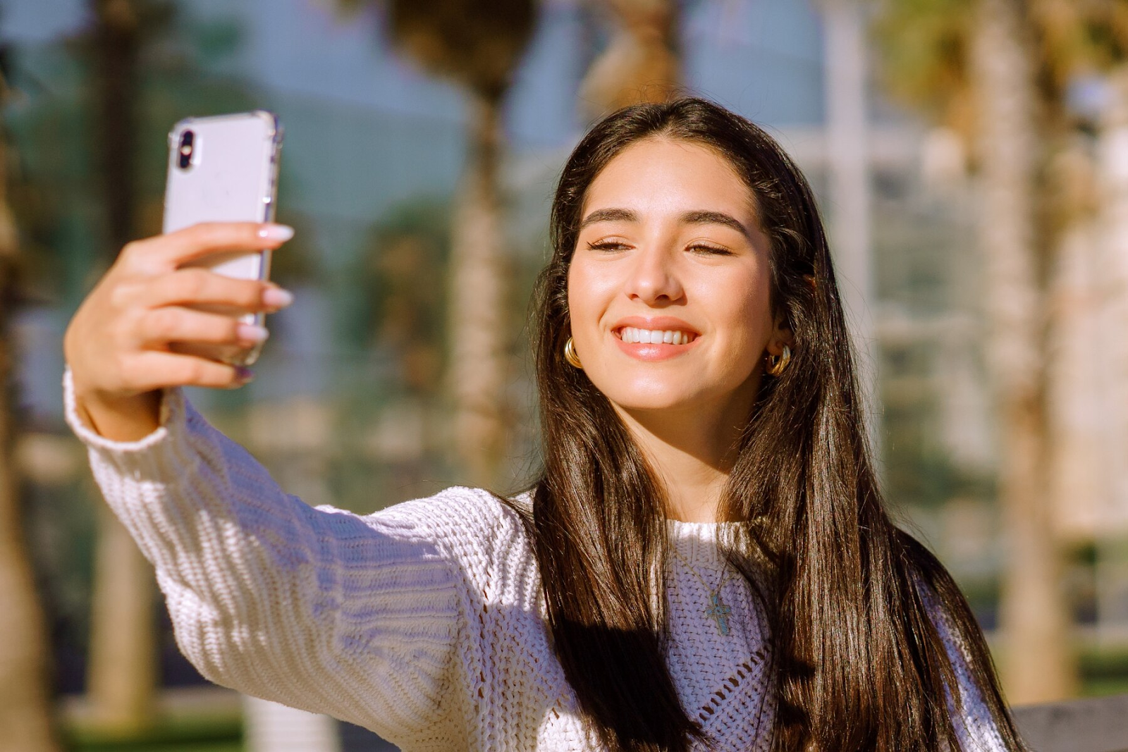 A woman smiling and taking a selfie.