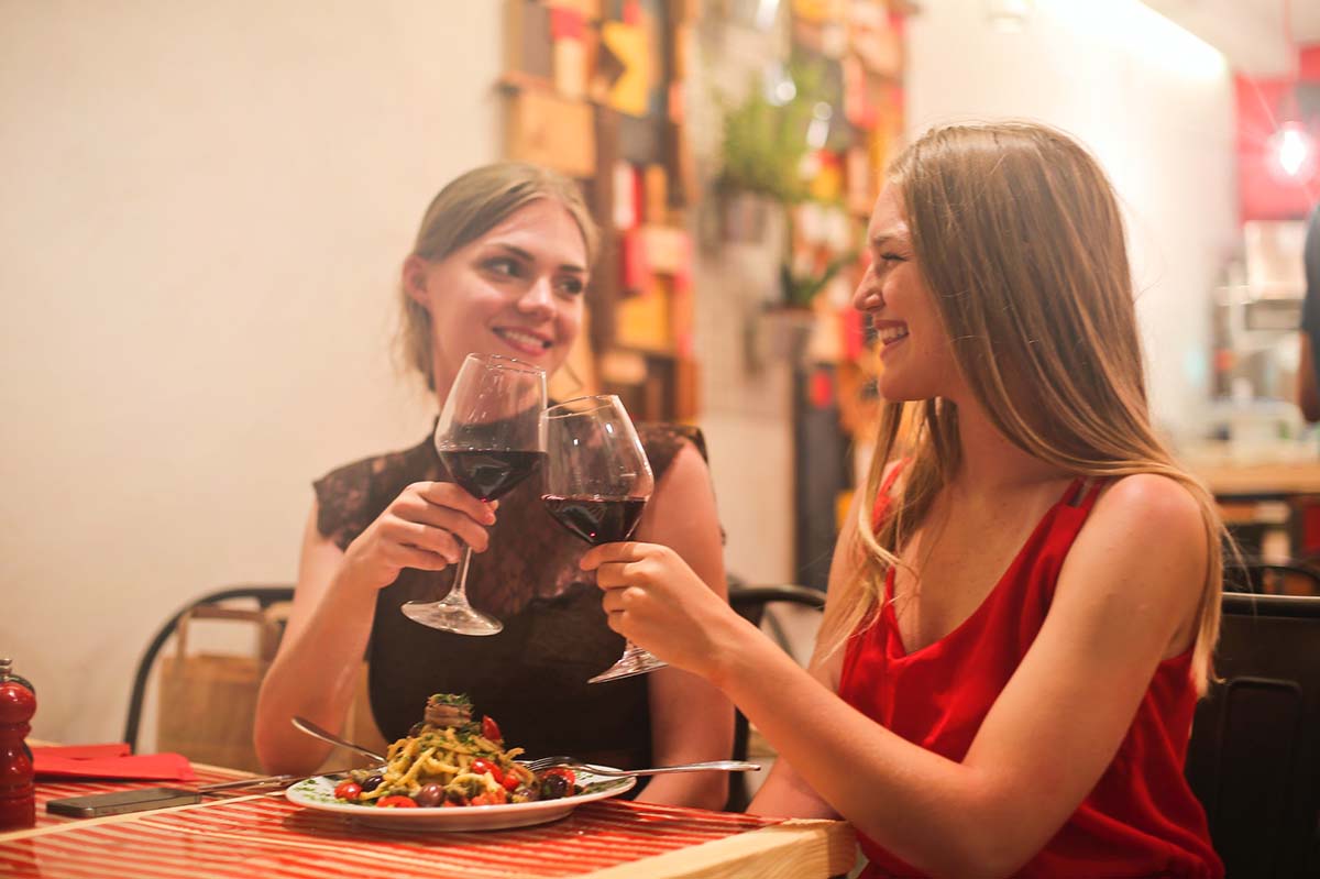 Women clinking wine glasses and sharing a plate on a night out.