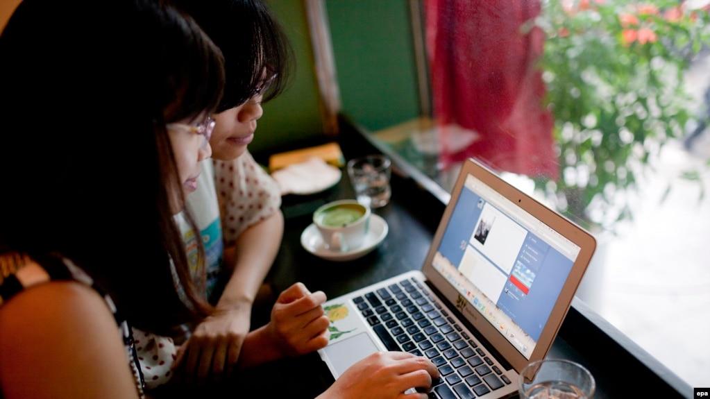 Hai bạn trẻ vào mạng xã hội ở một quán cà phê tại Hà Nội