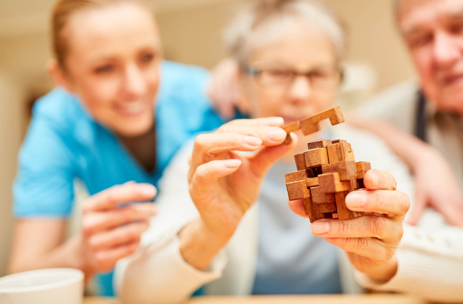 A senior woman works on a puzzle with the support of a nurse.
