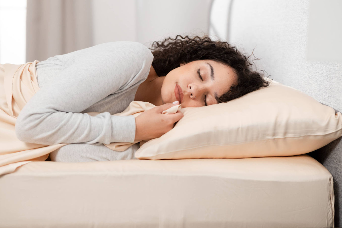 A woman sleeping with Hush Bamboo Sheets in Iced Latte color.