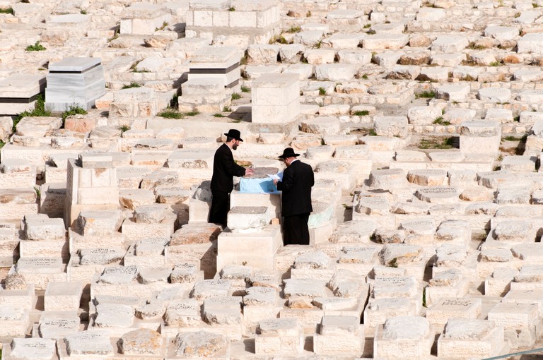 Orthodox Jews prying at one of the tombs in the cemetery on the Mount of Olives Jerusalem, Israel