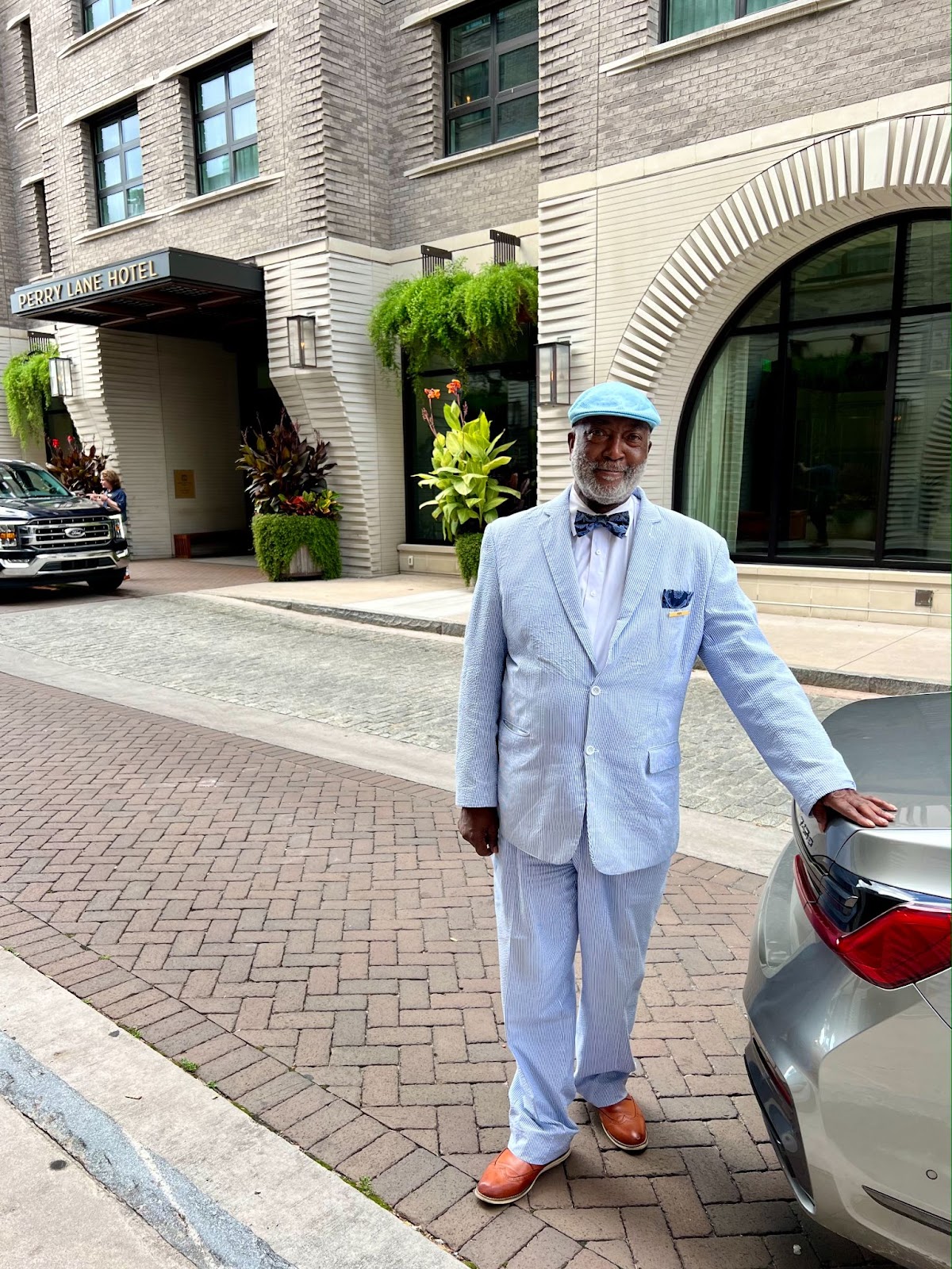 a man in a blue suit standing on a sidewalk