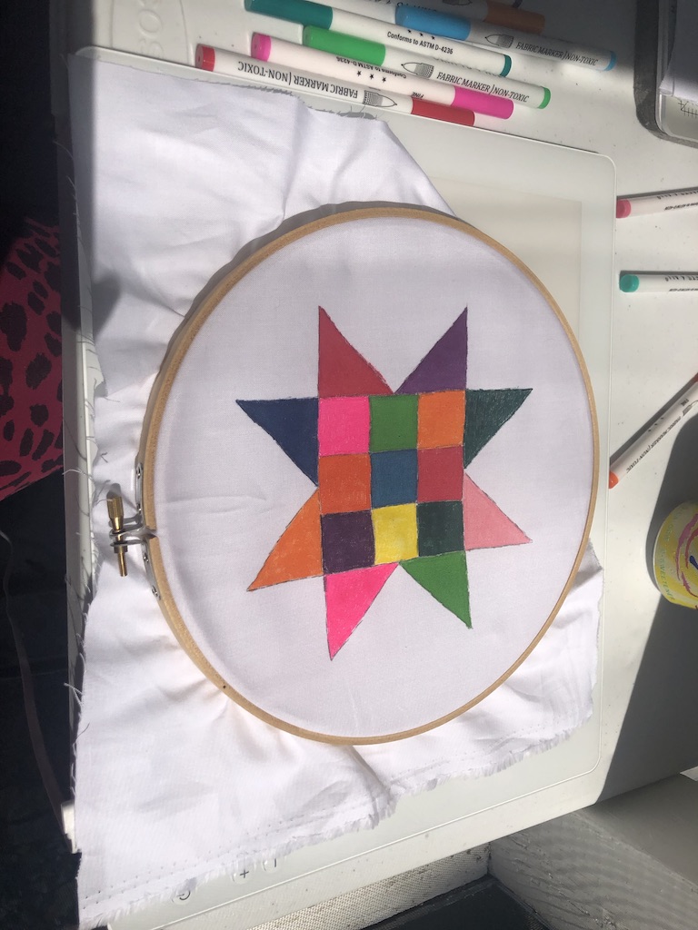 The quilt's colored design on an embroidery hoop. 