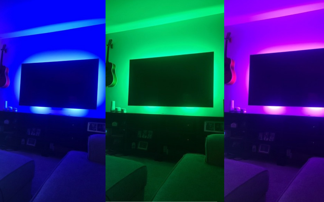 Television mounted on wall backlit by blue, green, and purple lighting. 
