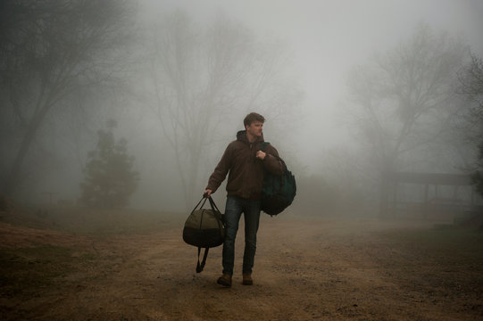 Man with backpack walking in fog on field