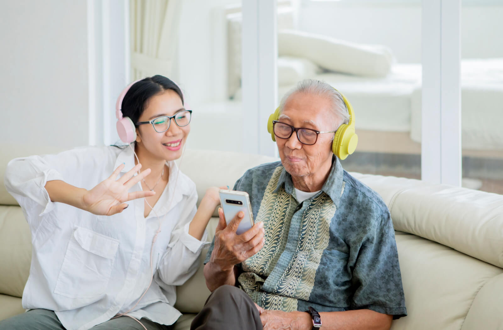 A young woman listening to music with her senior father. Both of them using a headset.