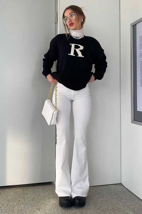 a lady wearing white high-rise flared jeans with a sweater and sneakers