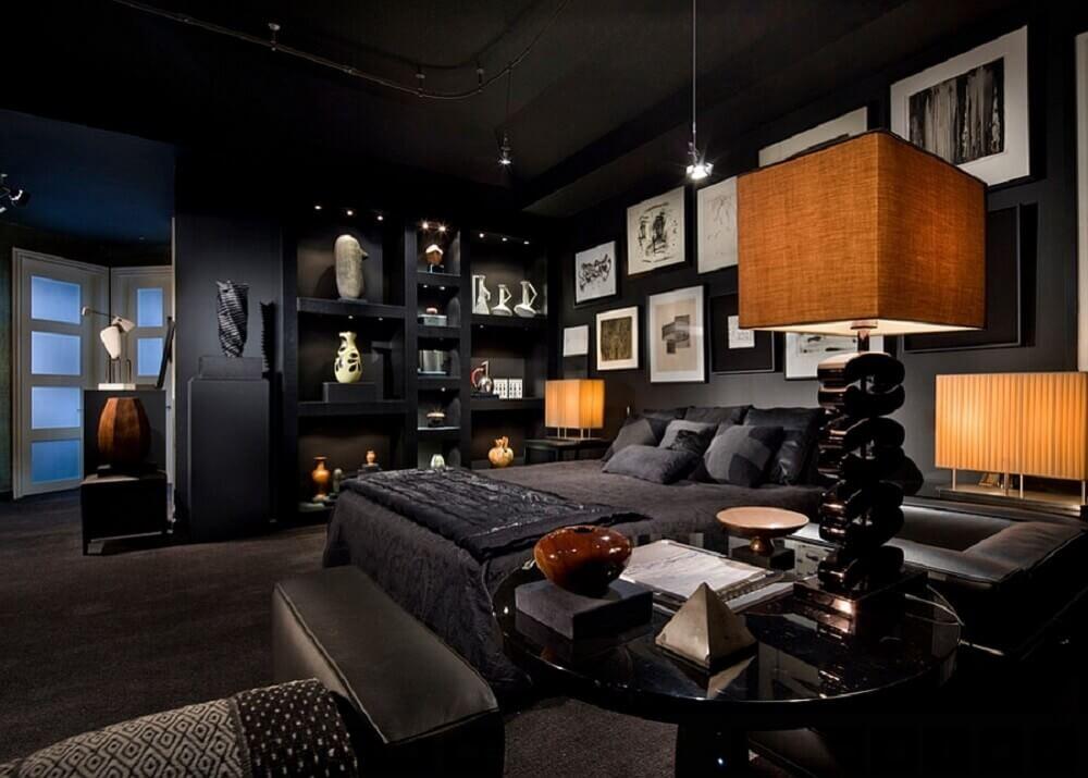 Quarto com cama de casal com paredes, teto e piso preto, móveis, cama e poltronas pretos e quadros e objetos decorativos branco e amadeirado.