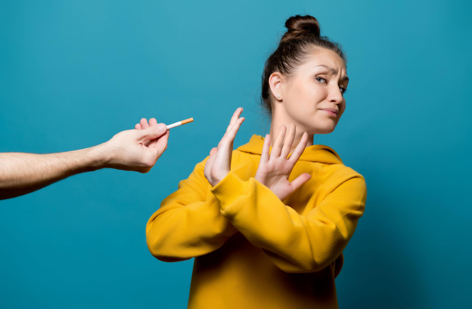 A woman rejecting a cigarette by crossing her hands.