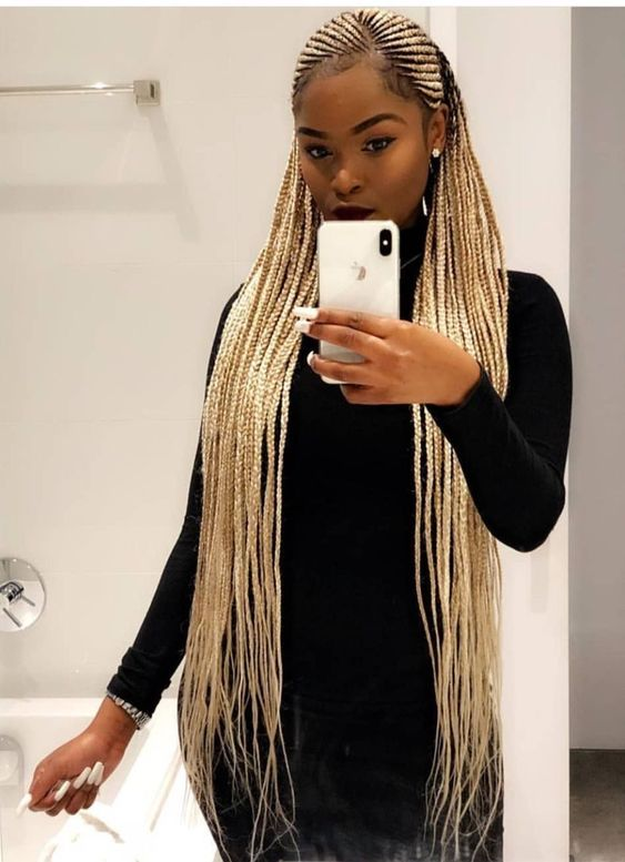 a lady holding a phone while rocking Fulani braids blonde hairstyles