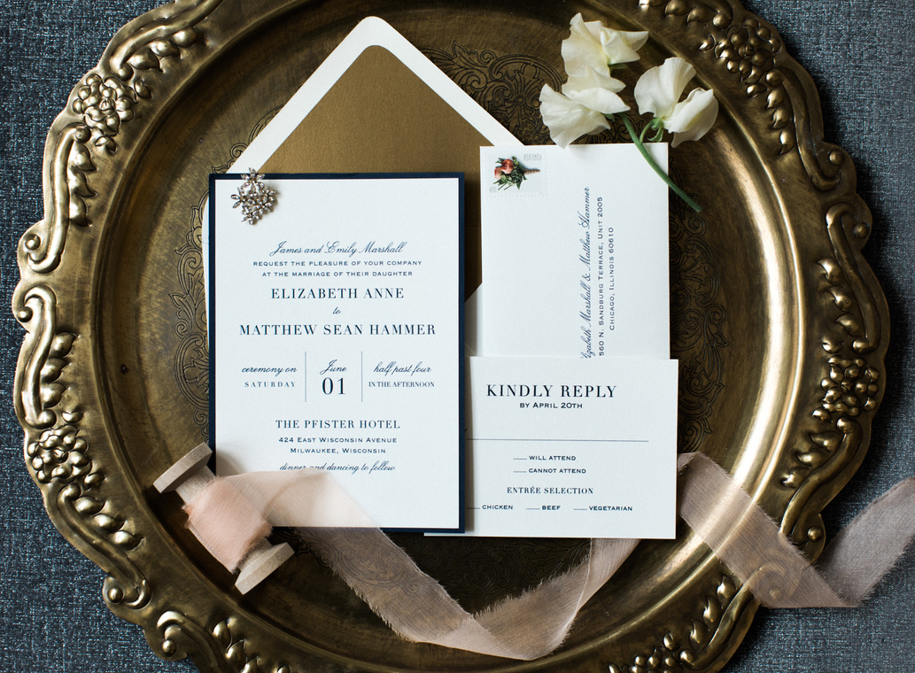 Wedding invitation suite on gold platter.