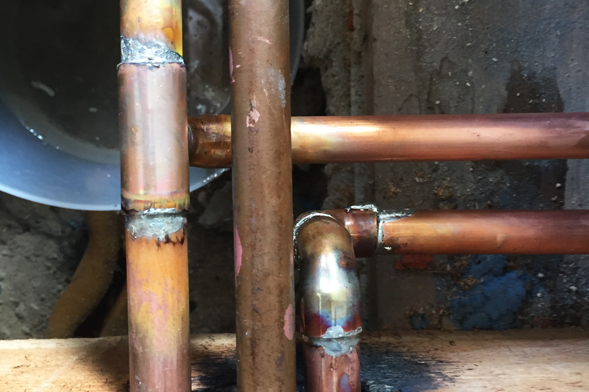 A few copper pipes in front of a concrete wall