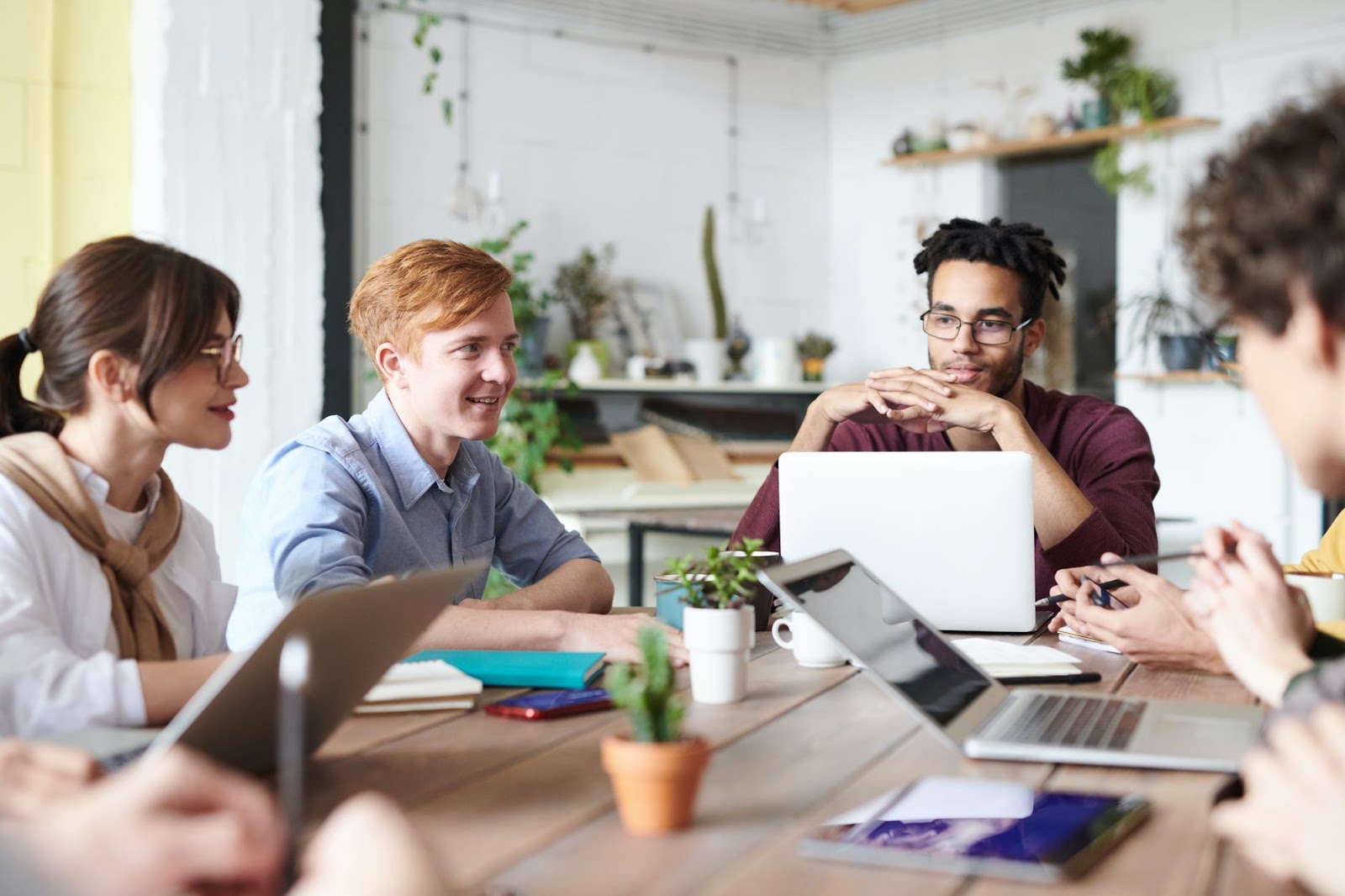 A group of colleagues working together at a table in front of their laptops
