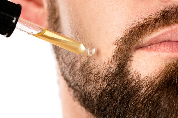 A closeup shot of a man applying beard oil to his beard