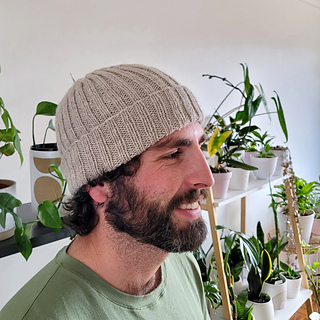 man wearing a classic ribbed beanie in front of potted plants