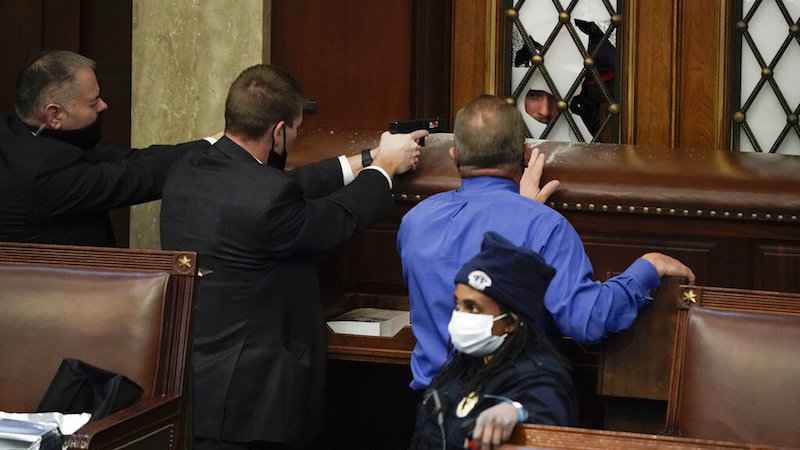 Police with guns drawn watch as protesters try to break into the House Chamber at the U.S. Capitol on Wednesday, Jan. 6, 2021, in Washington.