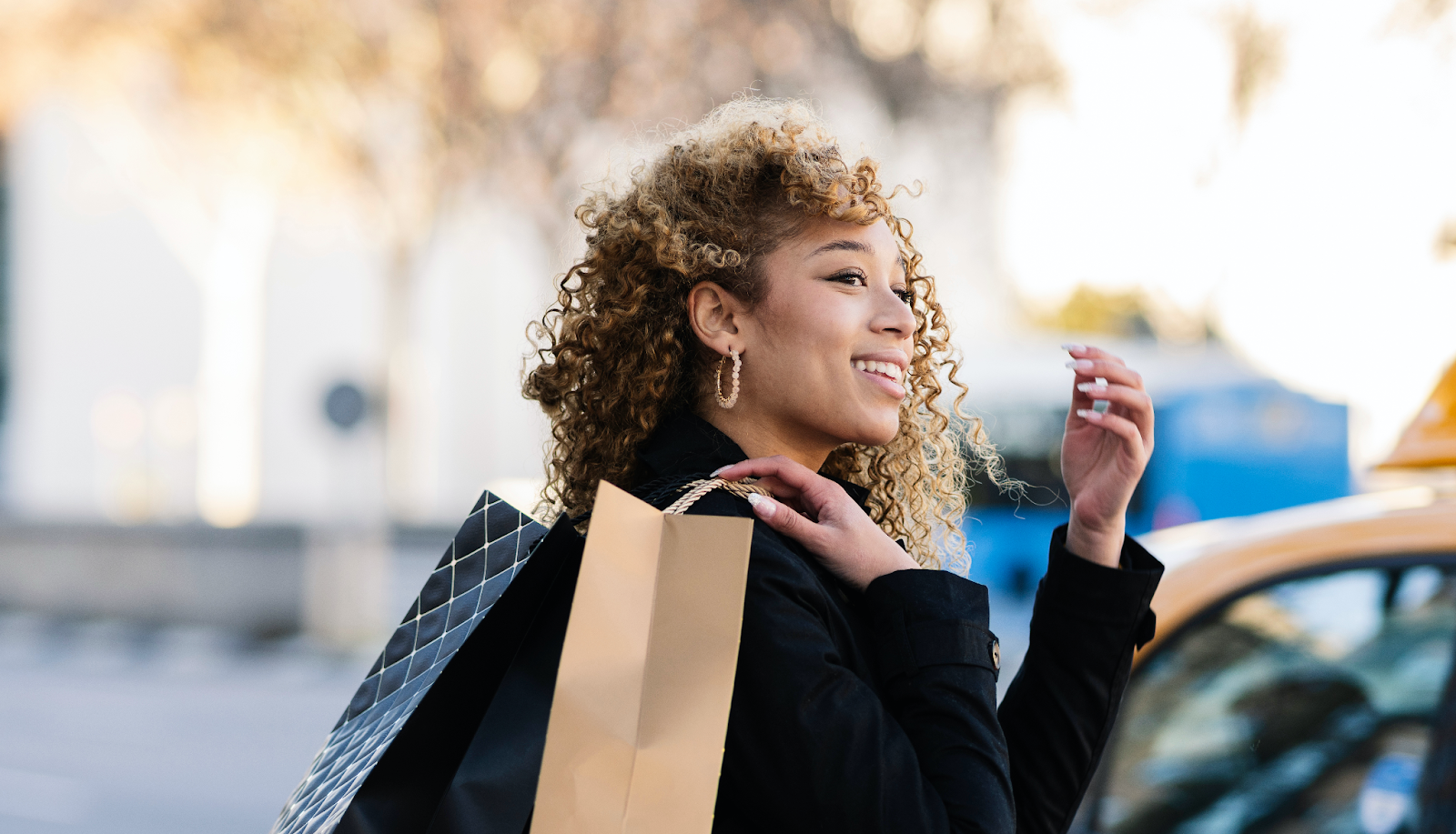 mulher atravessando a rua usando um blazer preto com sacolas de compras na mão