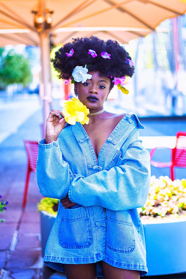 mulher negra segurando flores e com várias flores em seu cabelo