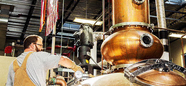 A Distiller Works The Copper Still At Ghost Coast Distillery
