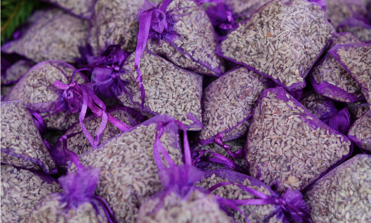 Dozens of purple lavender sachets for repelling moths in storage containers.
