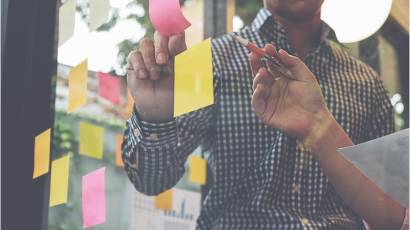 Man sticking notes to planning board in office