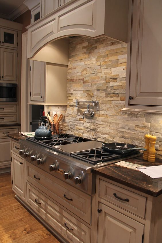 large traditional kitchen with off white cabinets, black hardware and warm colored stone backsplash