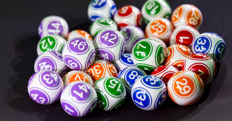  Bolas de bingo de diferentes colores agrupadas en una mesa negra. Máquina y equipo de juego.