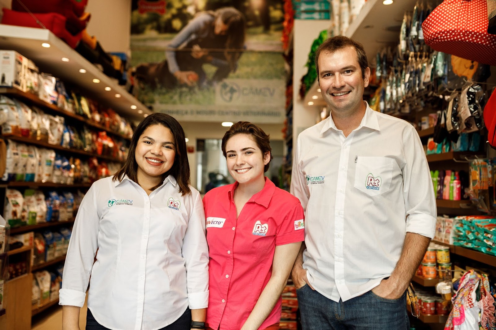Funcionários de pet shop uniformizados sorrindo na frente da loja