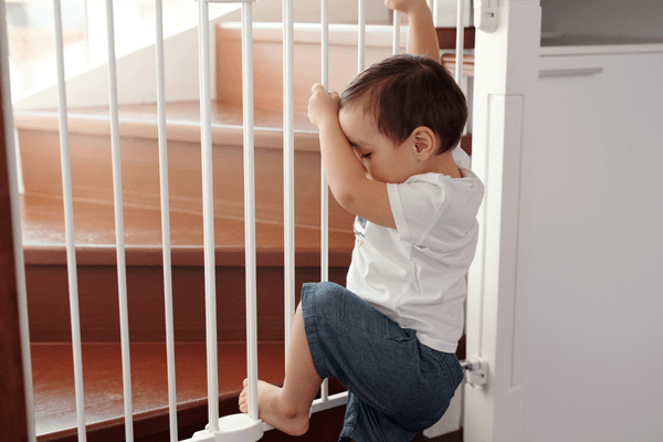 Baby trying to climb over an installed stairwell baby gate