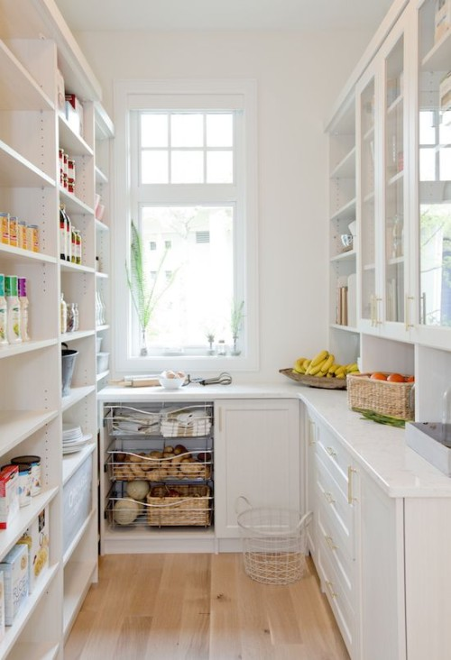 modern white pantry with natural light, floor to ceiling shelving, glass door cabinets, white countertops, wire shelving and wood floors