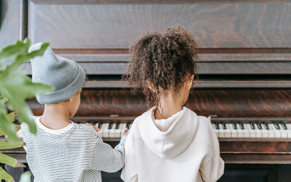 two children sitting beside each other playing piano