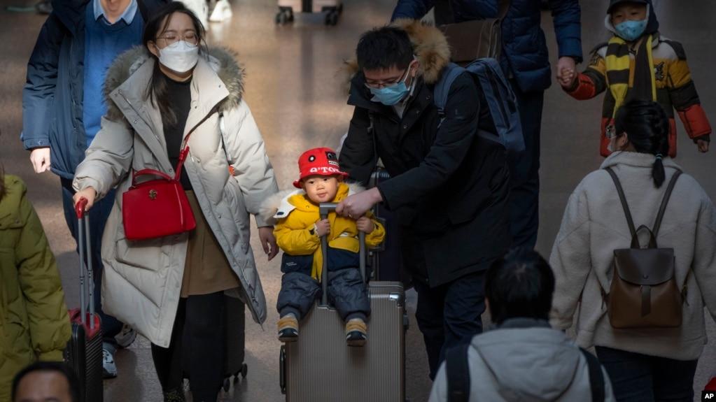 北京西站,2023年1月18日,一位男士推着坐在手提箱上的孩子。中国人口出生率开始缓慢下降,使中国领导人面临新的考验。