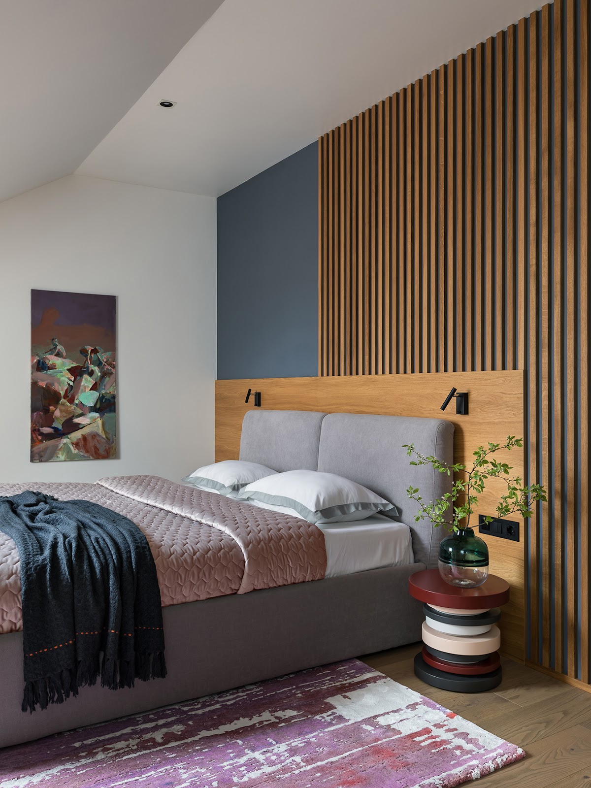 Phòng ngủ ấn tượng bởi rất nhiều những màu sắc kết hợp sinh động từ chăn ga gối đến táp đầu giường như màu hồng, xám, đỏ, tím, đen, xanh ngọc lục bảo,... Đặc biệt là bức tranh treo tường và tấm thảm trải sàn 'loang lổ' khác biệt.