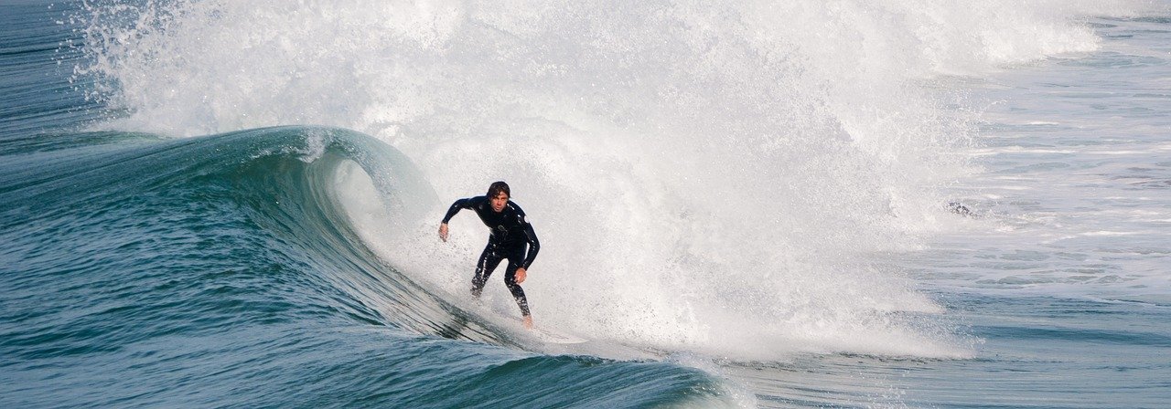 A man surfs wearing a wetsuit.