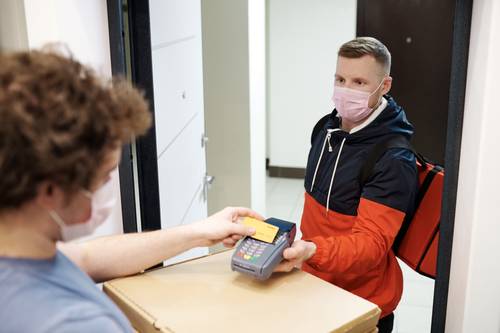Person Wearing a Face Mask Paying for a Delivery