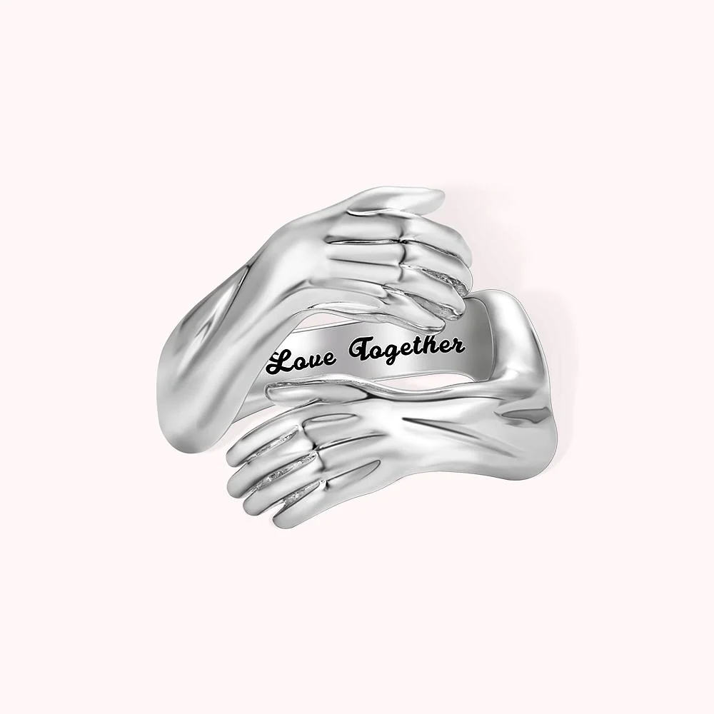 Bague avec anneau personnalisée par la phrase Love Together sur la face extérieure. Le tout est entouré par deux bras en position de câlin.